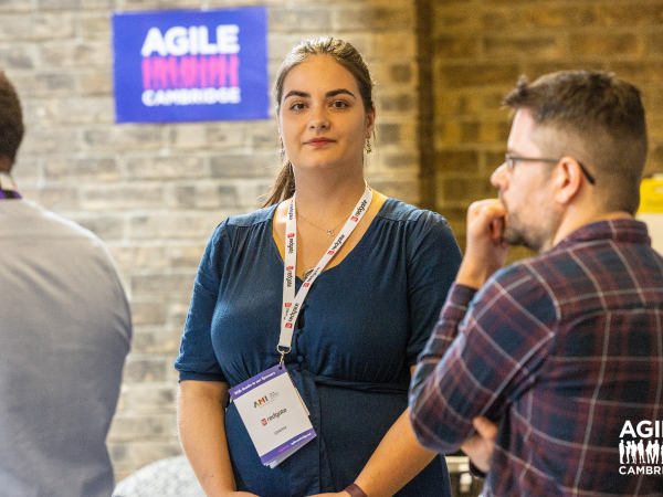 Two participants at Agile Cambridge, one person in looks straight into the camera